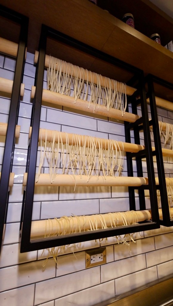 Fresh pasta strands hanging to dry on wooden rods